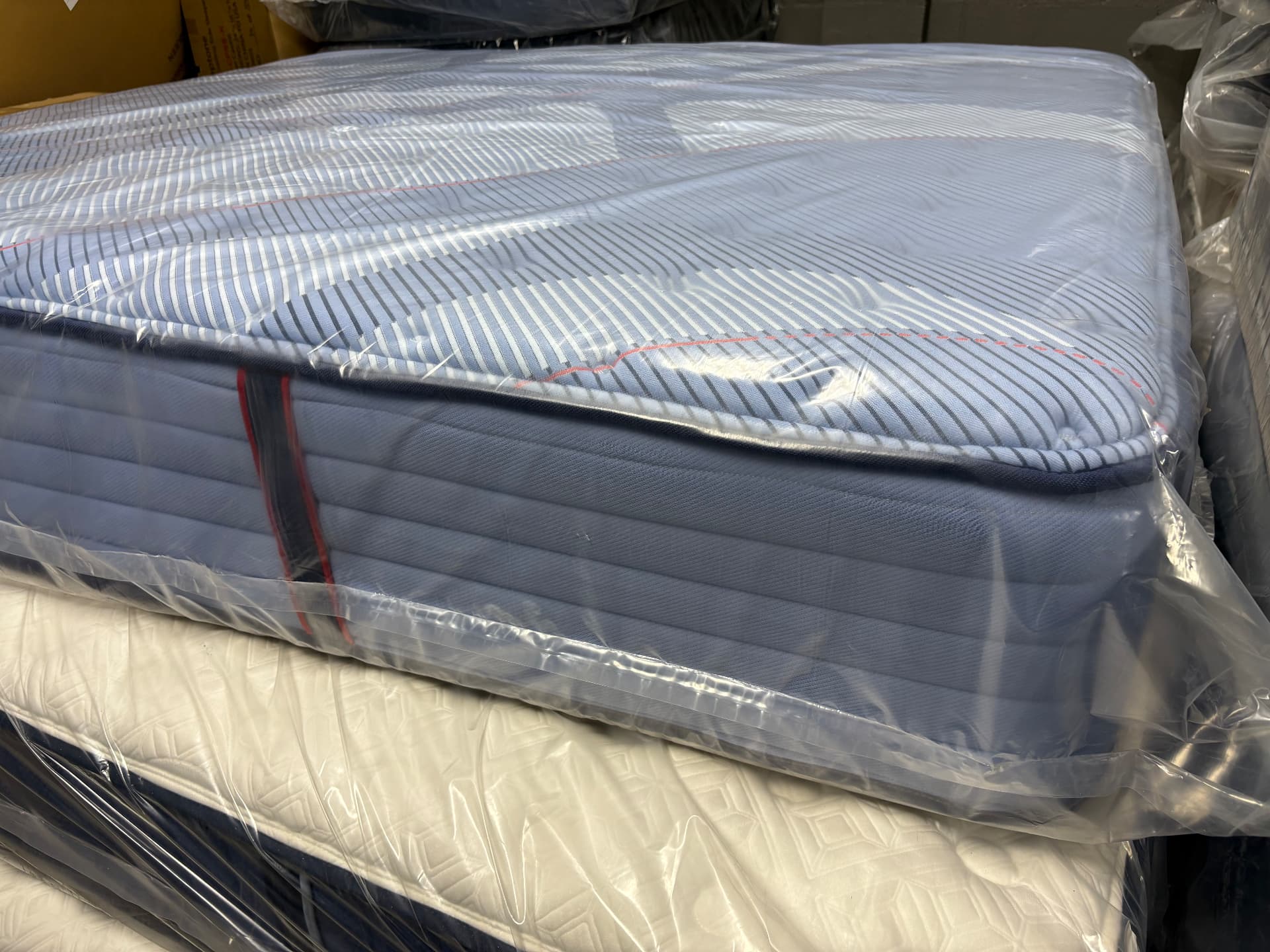 Blue-sided mattress with a striped top in protective wrapping